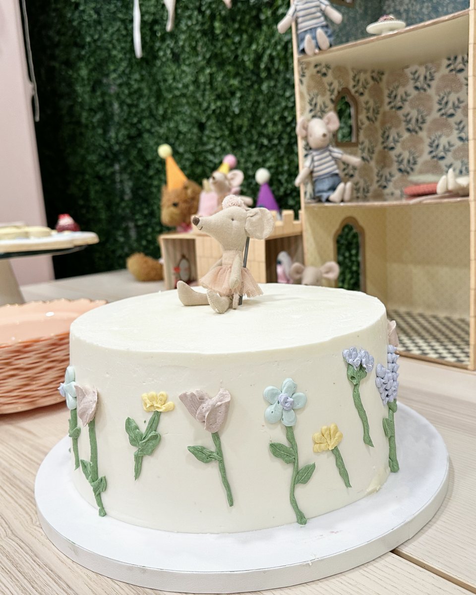 White birthday cake with painted flowers and a little mouse topper