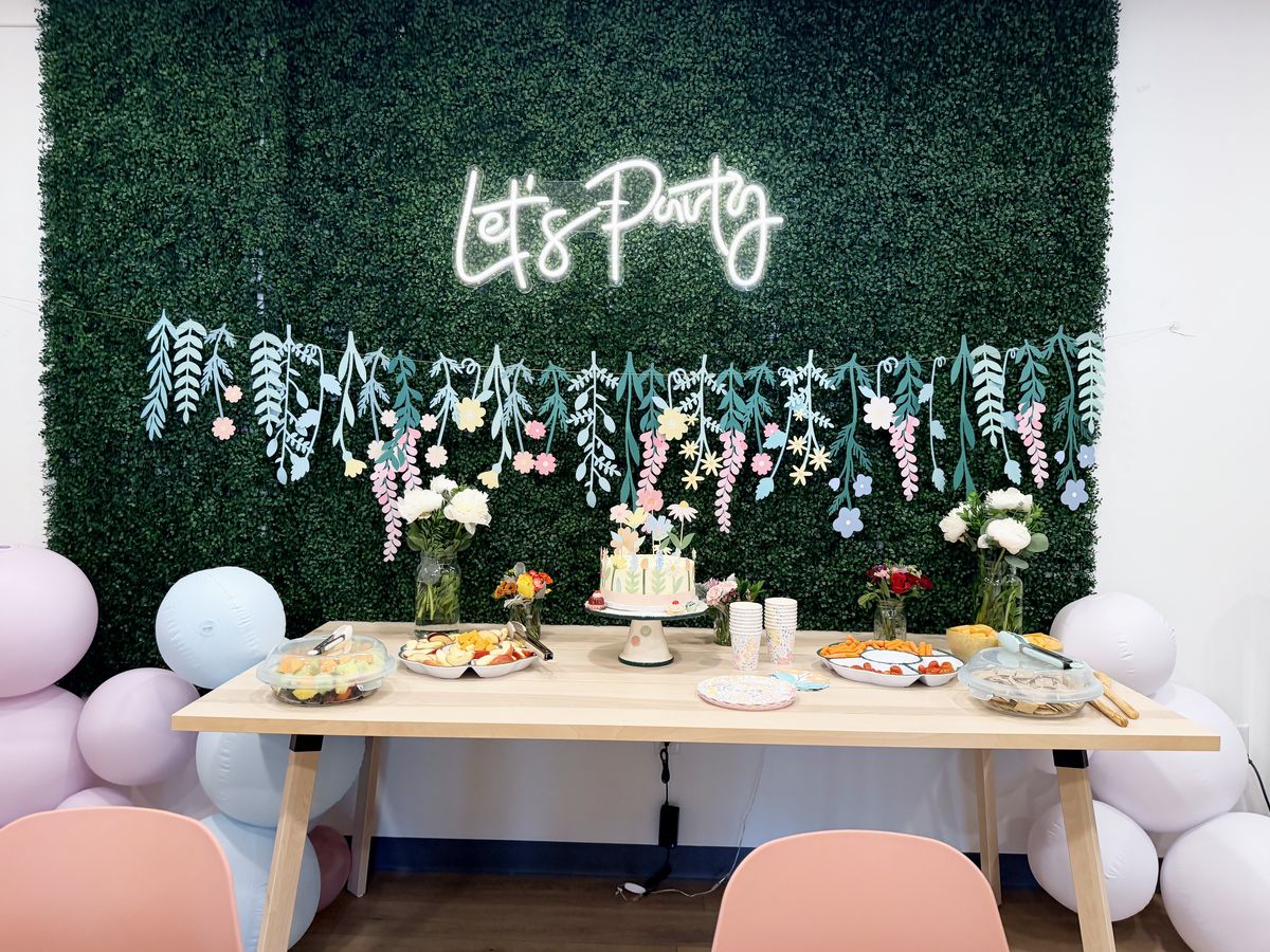 Party room with a Let's Party neon sign, balloons and a decorated table